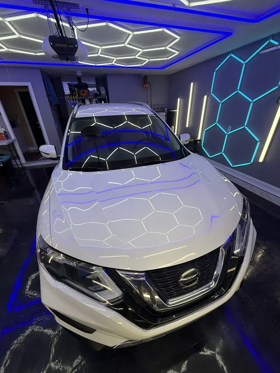 Hex shop lights reflecting off the hood of a white 2020 Nissan Rogue after a full detail in Panama City FL
