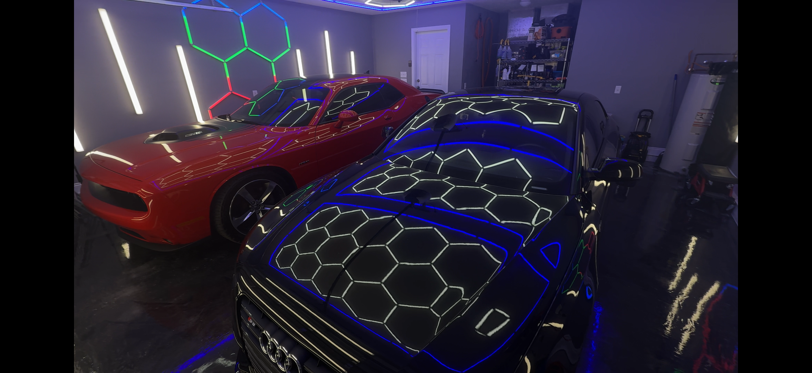 Two ceramic coated cars under hexagonal studio lights at Ceramico