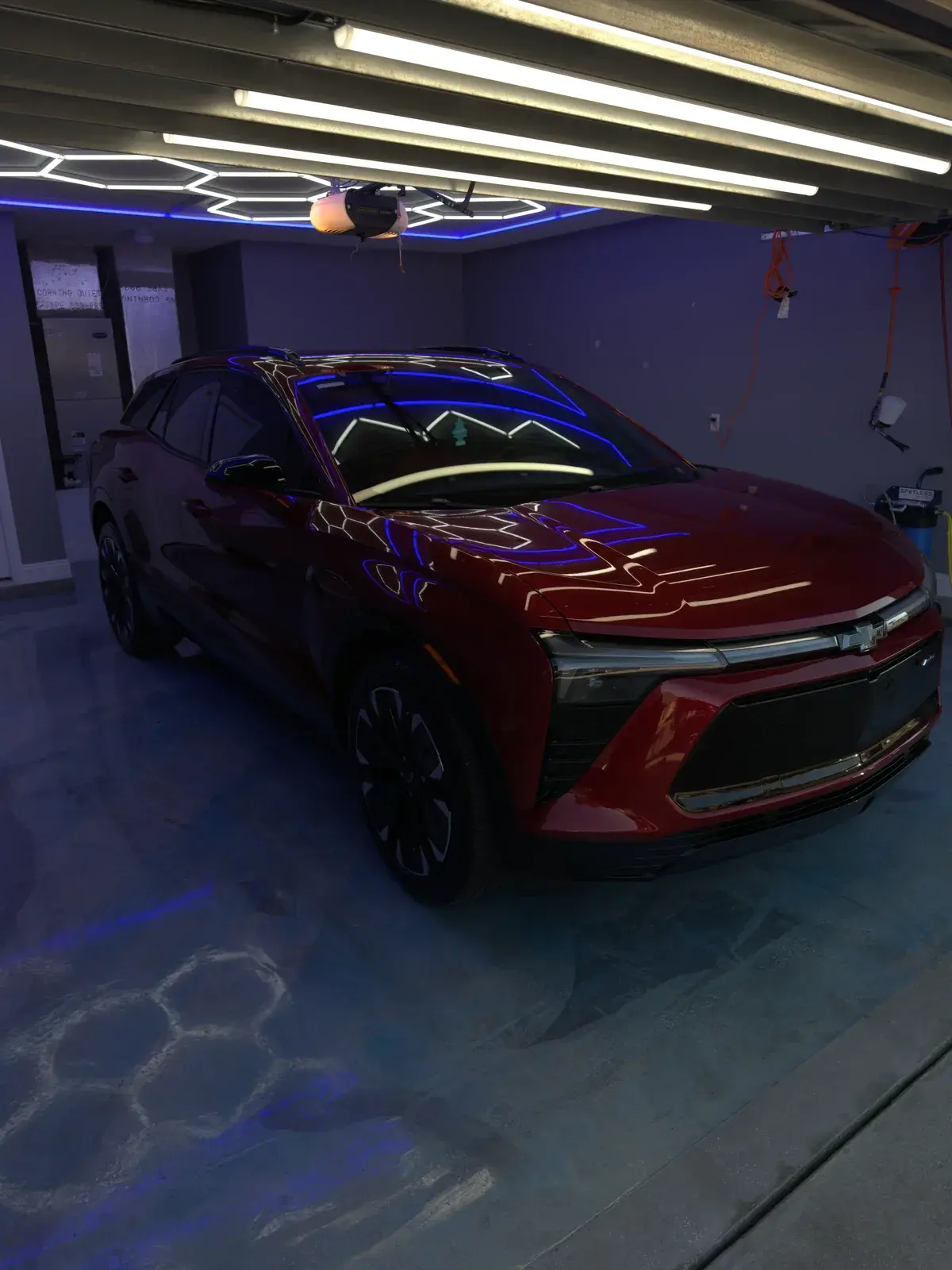 Front three-quarter view of a red 2024 Chevy Blazer EV with a fresh ceramic coating under the shop lights in Panama City FL