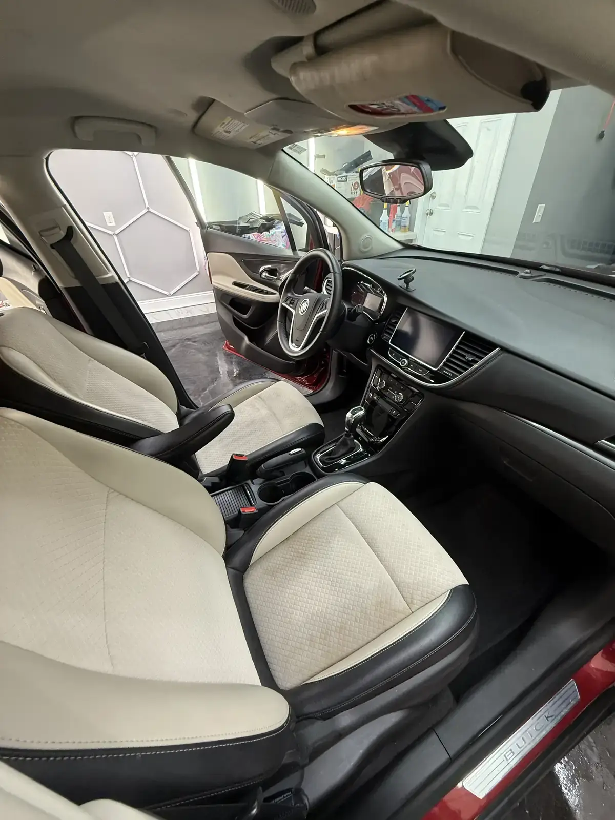 Clean light cloth seats and dashboard of a 2019 Buick Encore after an interior detail in Panama City FL