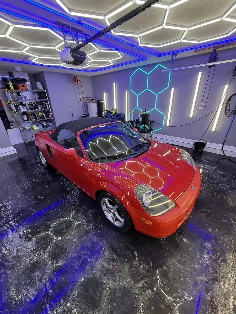 Red 2001 Toyota MR2 Spyder convertible under the hex shop lights after a full detail in Panama City FL