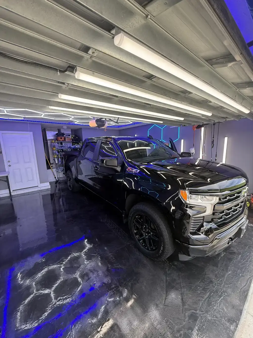 Black Chevy Silverado with black wheels after a ceramic coating under the hex shop lights in Panama City FL