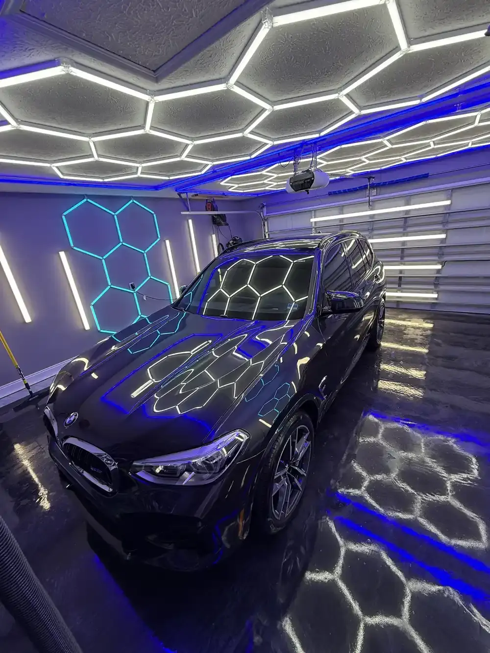 Dark BMW X3M under the hex shop lights after a full interior and exterior detail in Panama City FL