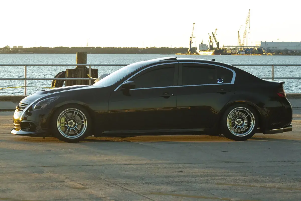 Side profile of a ceramic coated black Infiniti G37 sedan on the waterfront in Panama City FL